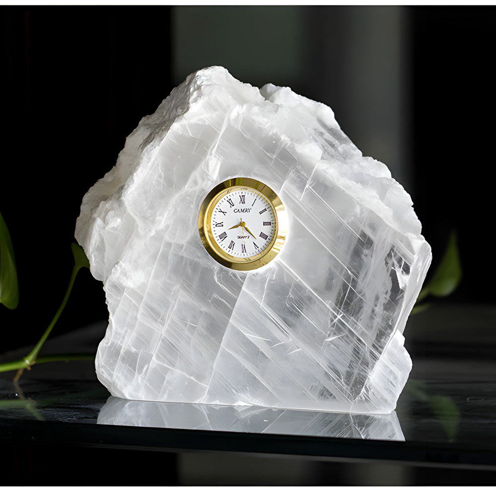 Small Selenite Mineral Table Clock on a dark reflective surface with soft greenery
